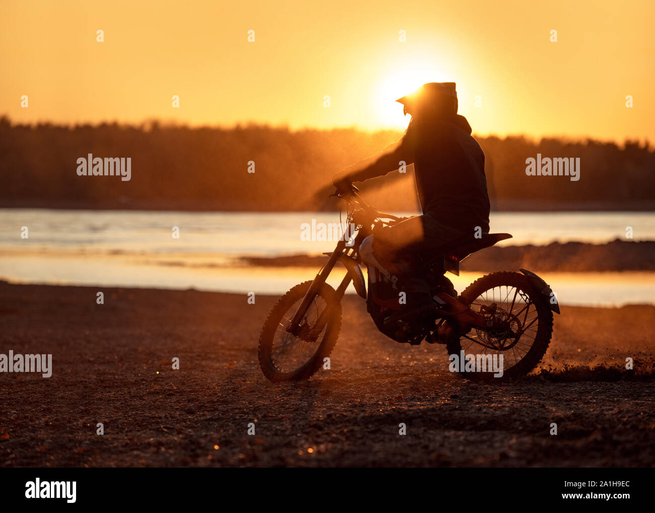 Der Motorradfahrer Silhouette auf elektrischen Motorrads im Abendlicht und Staub Stockfoto