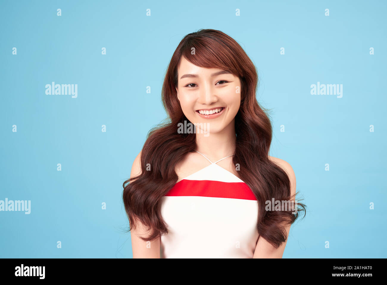 Asiatische Frau lächelnd mit Freizeitkleidung, blauer Hintergrund Stockfoto