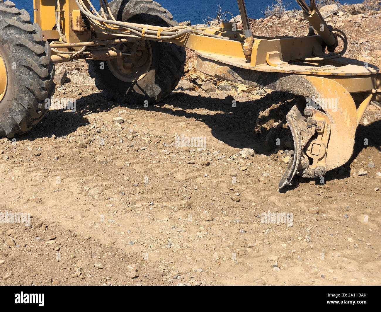 Close-up Streichblech Planung Fahrbahn. Klinge der Motorgrader während der Straße Bauarbeiten. Erdbewegung, Ausgrabungen, Graben auf dem steinigen Boden Stockfoto
