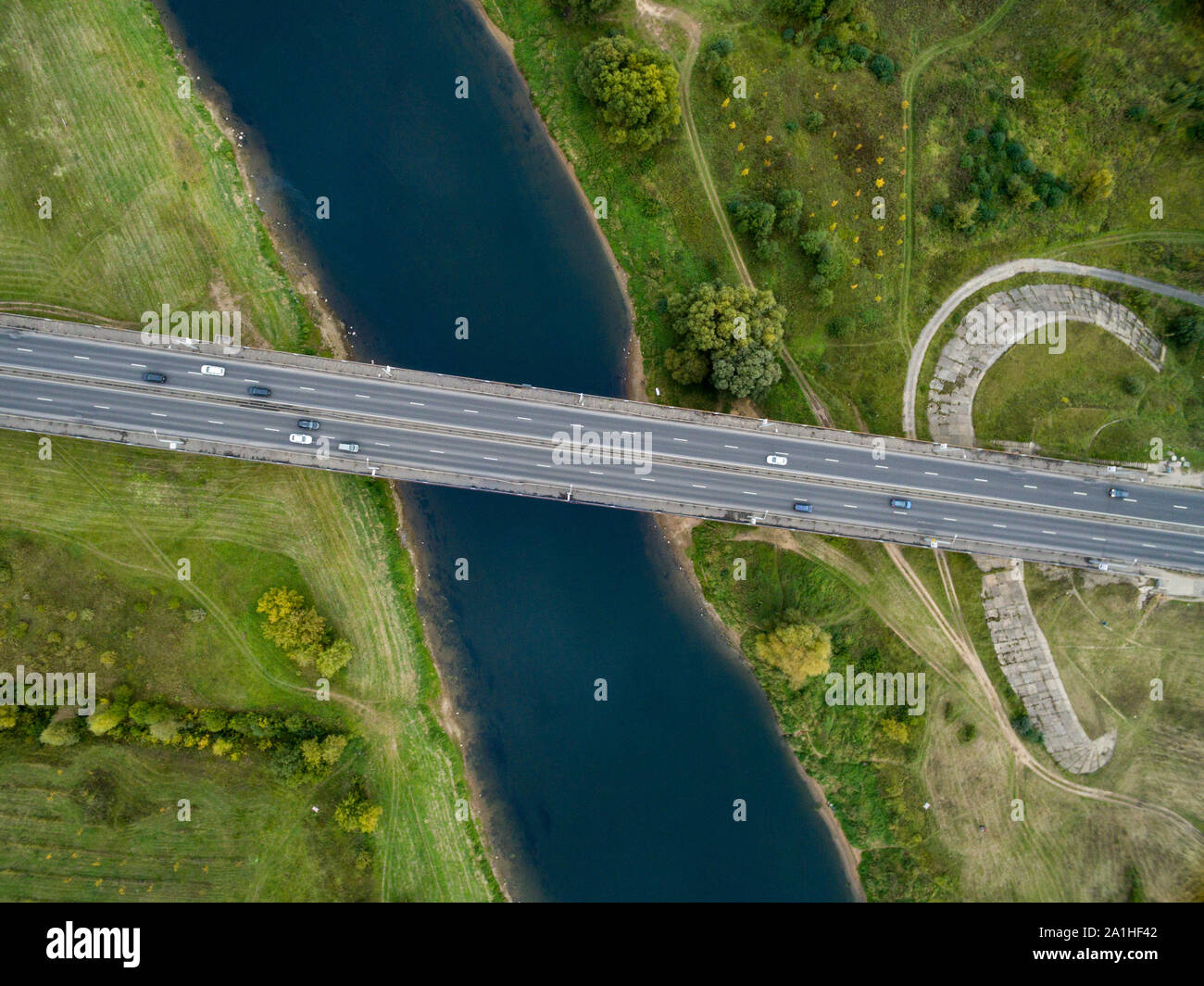 Landschaft von einer asphaltierten Straße mit Autos. Blick von oben auf die Brücke und Der blaue Fluss. Sommer Fotografie mit Bird's Eye View. Stockfoto