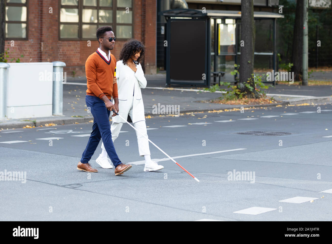 Junge Frau die Unterstützung blinder Mann auf der Straße Stockfoto