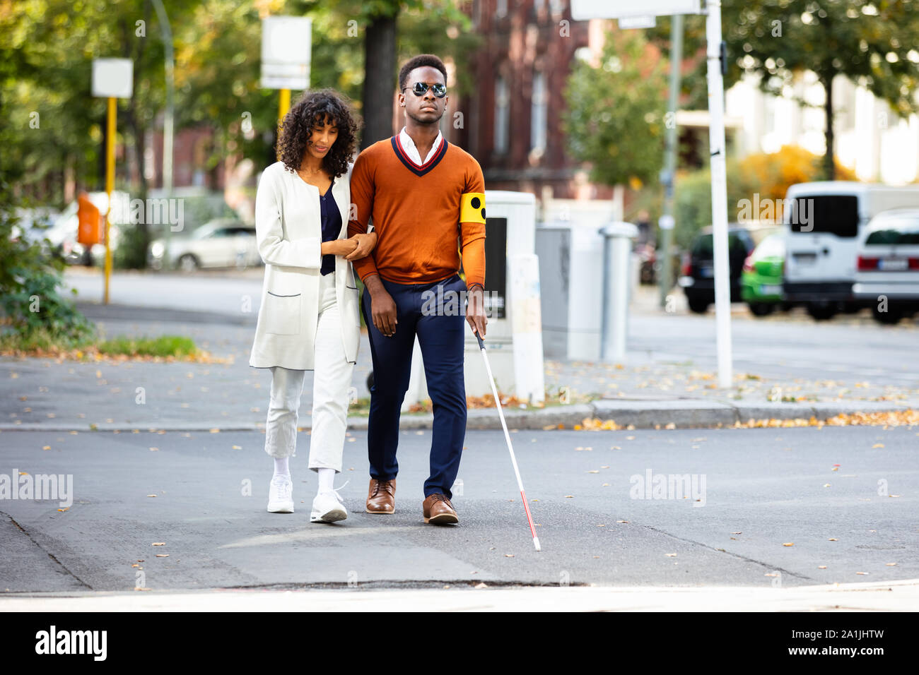 Junge Frau die Unterstützung blinder Mann auf der Straße Stockfoto