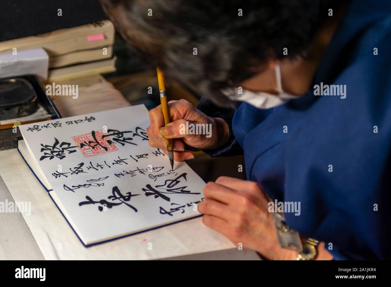 Frau schreibt japanische Schriftzeichen, Kalligraphie, Glücksbringer in den Todaiji Tempel, Japan, Nara, Japan zu Kaufen Stockfoto