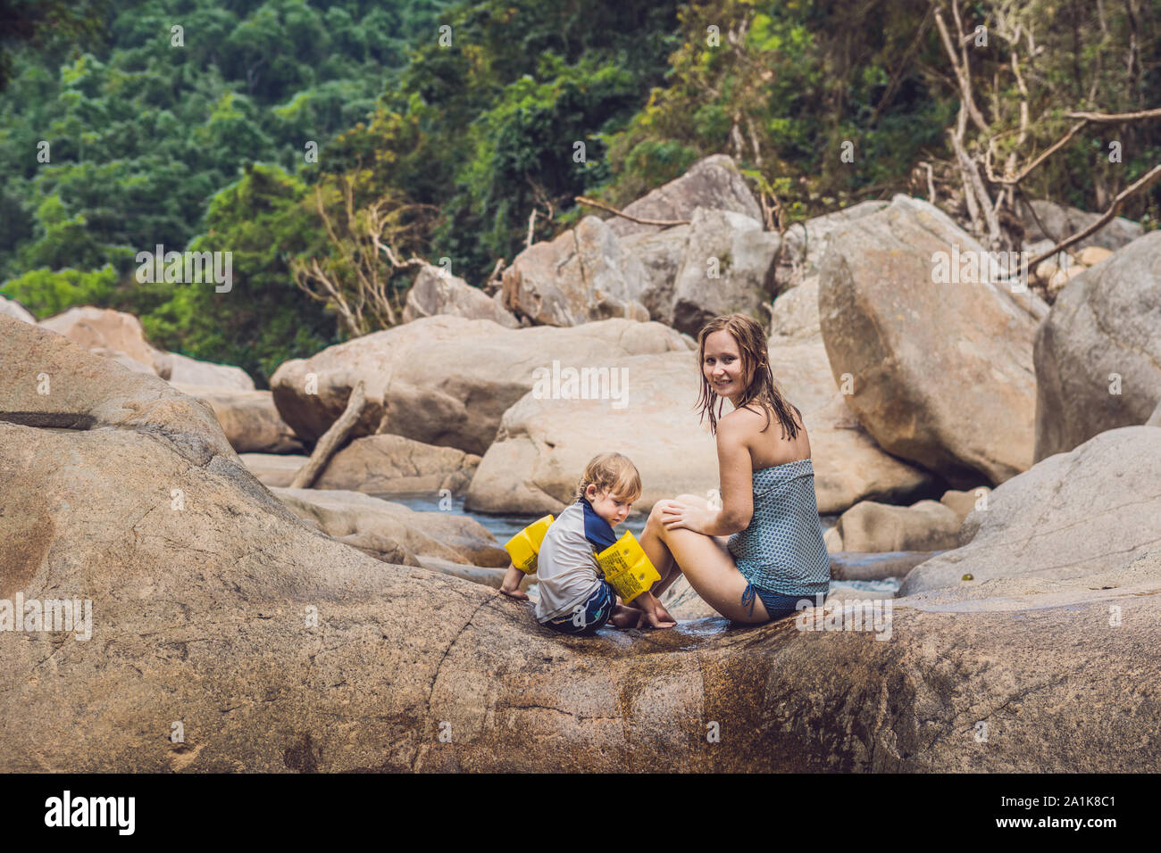 Mutter und kleiner Sohn auf einem Hintergrund aus Steinen und einem Fluss. Reisen mit Kindern Konzept Stockfoto