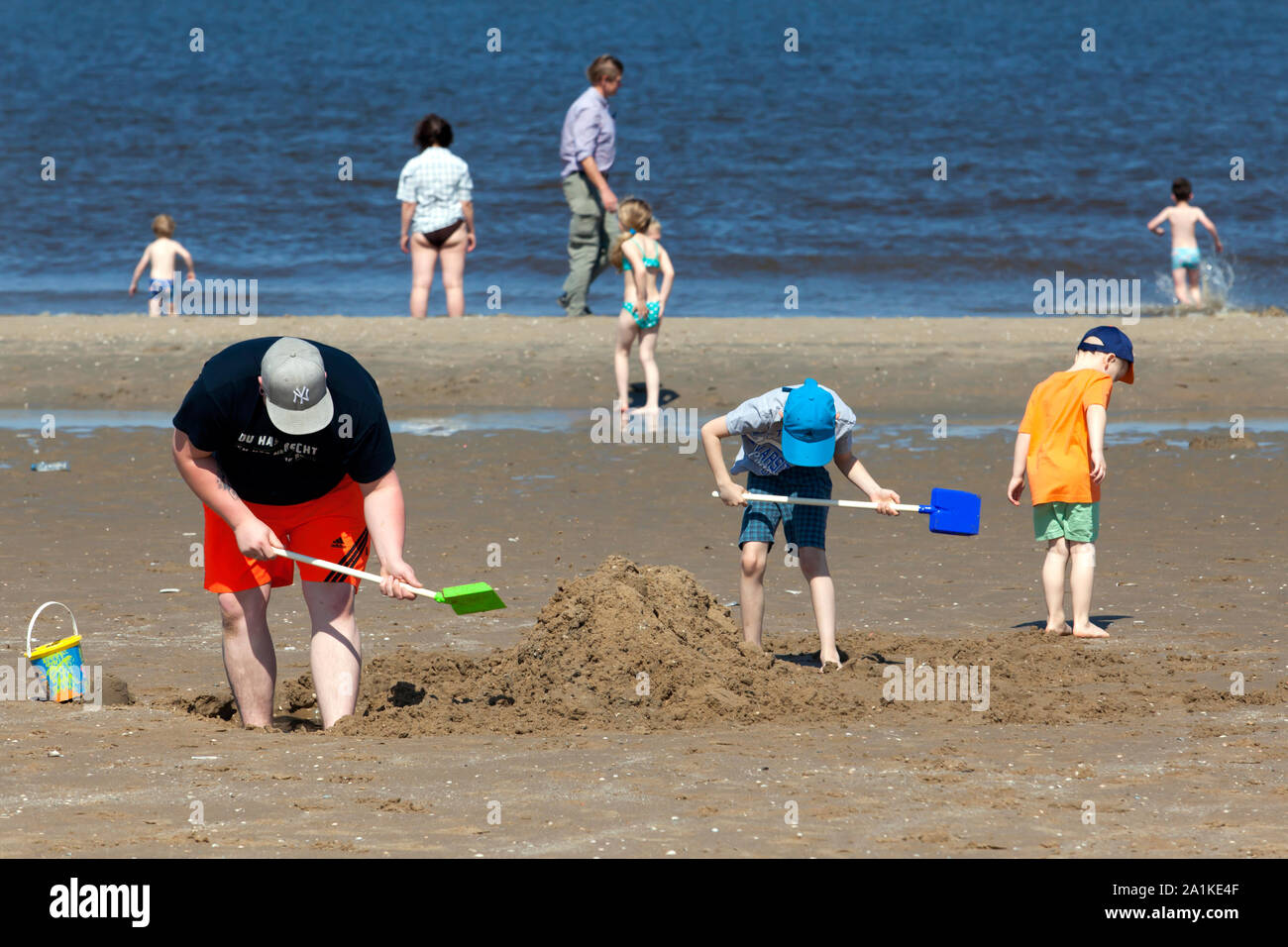 SCHEVENINGEN - Vater und Sohn graben Löcher in den Sand Stockfoto