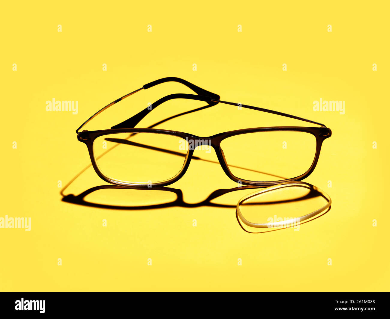 Zerbrochene Gläser, Brillen, objektiv auf gelben Hintergrund gefallen für Copyspace. Optische Gesundheit oder Brillen. Stockfoto