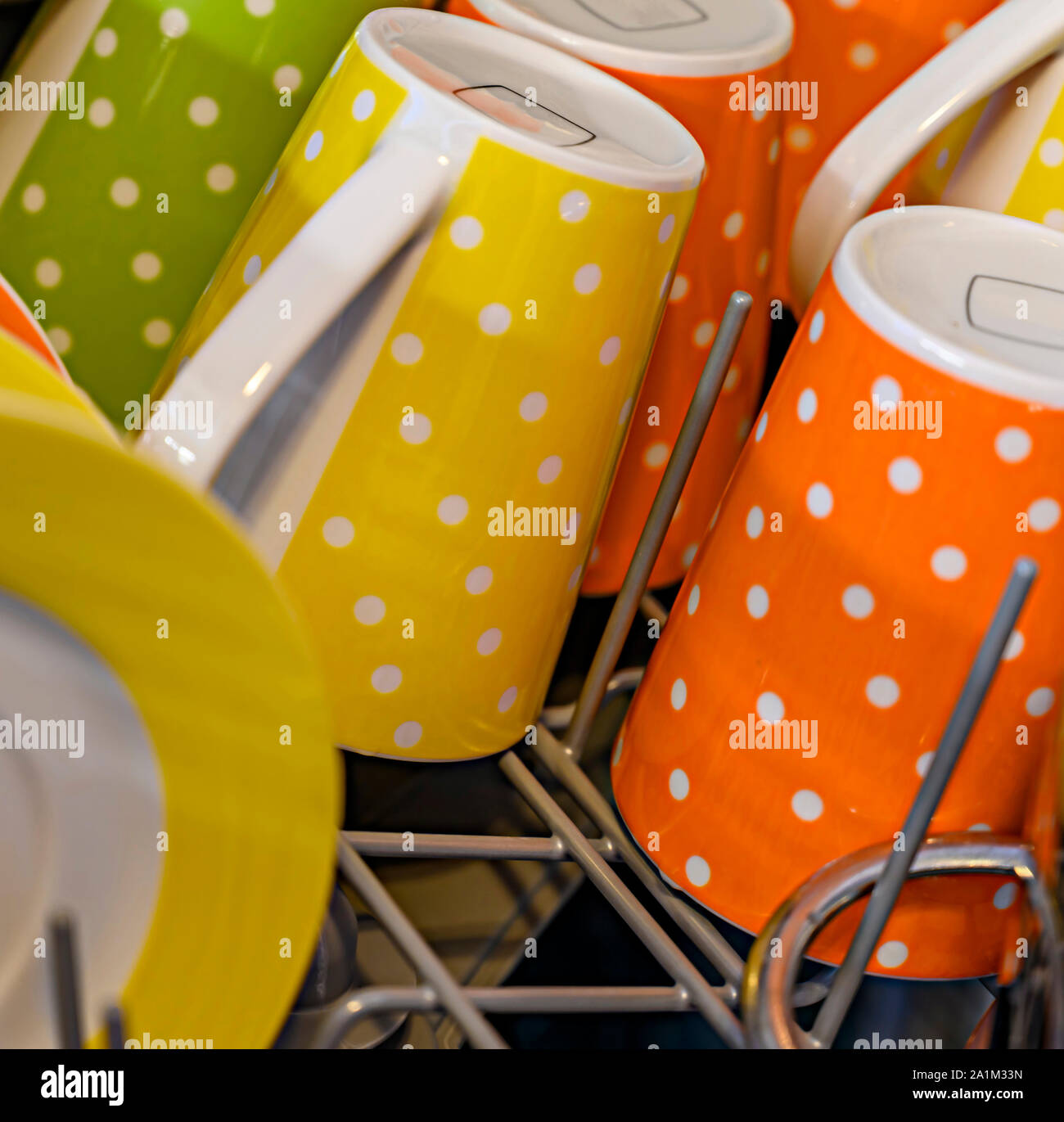 Bunte Tassen mit weißen Punkten in der Spülmaschine. Stockfoto