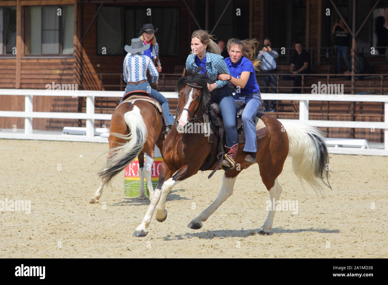 Weibliche Cowgirl und Cowboy in Barrel Racing Event mit Pferd Stockfoto