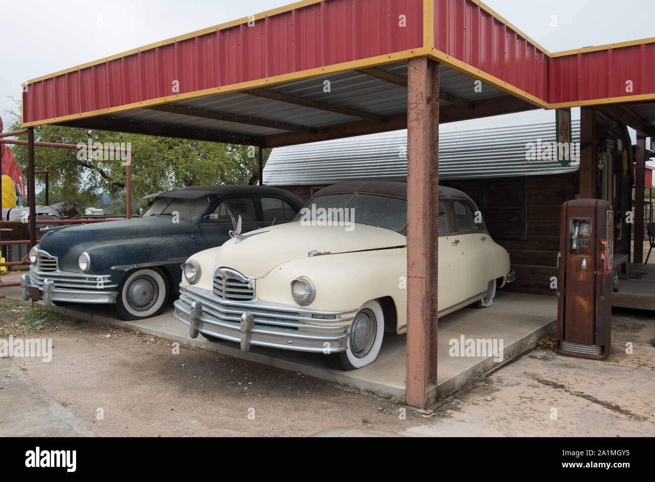 Alte Autos unter einer Markise an einem neu erstellt, Shell Tankstelle an der Töpferei Ranch Töpferei in Marble Falls, Texas Stockfoto