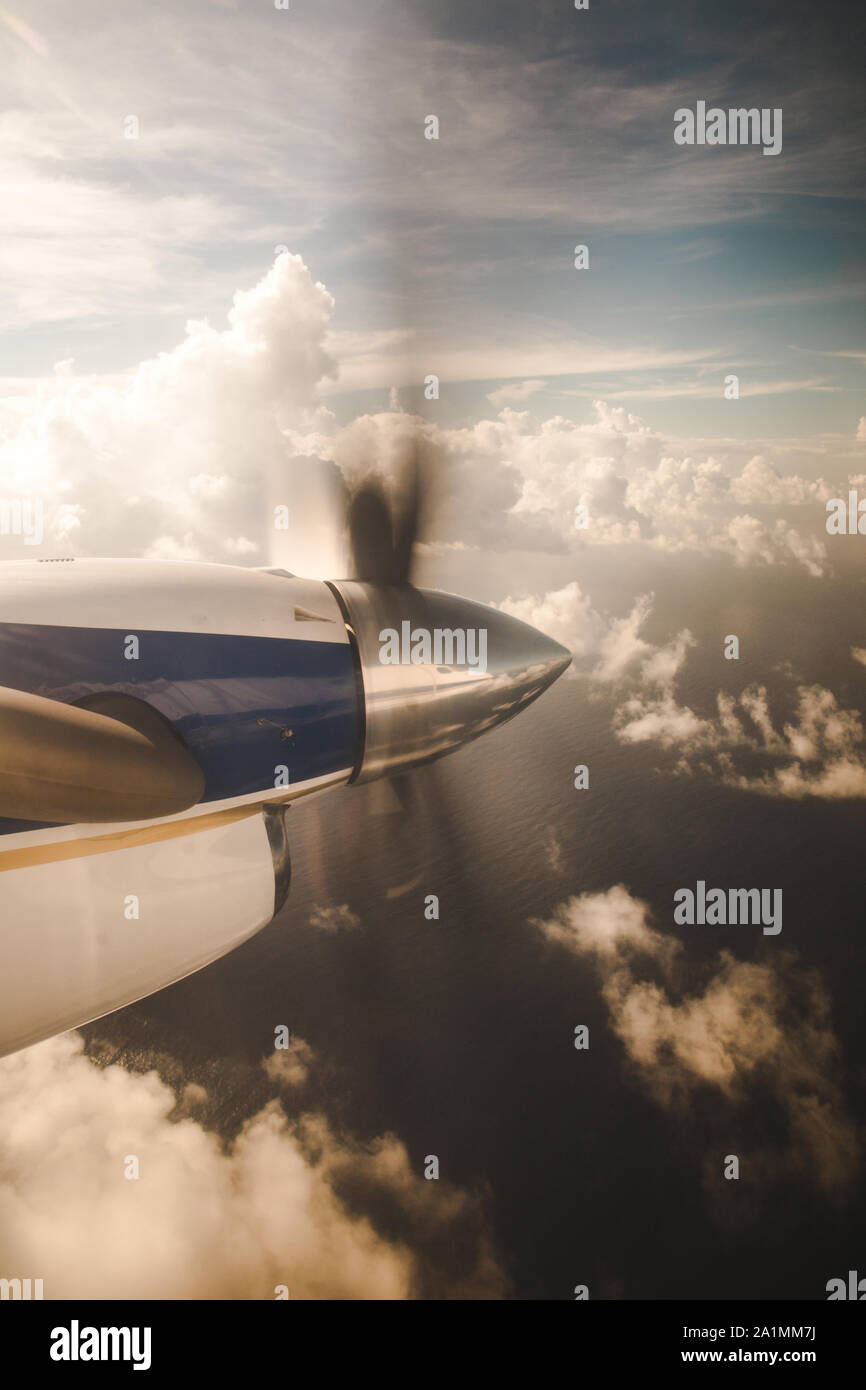 Kleines Propellerflugzeug, das über Wolken auf eine Insel im karibischen Meer fliegt Stockfoto