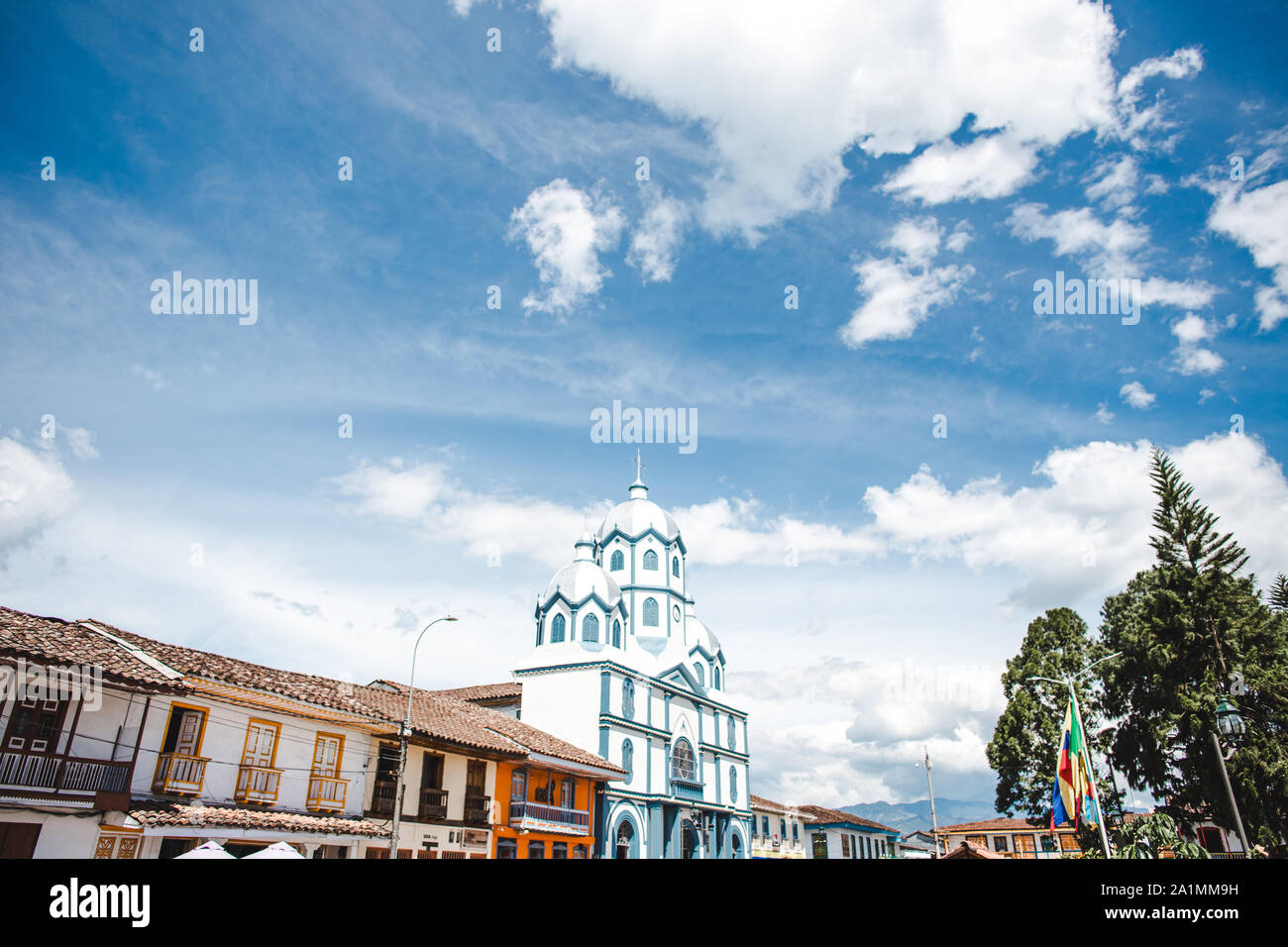 Farbenfrohe traditionelle Häuser und eine blau-weiße katholische Kirche auf dem hauptplatz von Filandia, einer typisch kolumbianischen Stadt in der Kaffeeregion Quindio Stockfoto