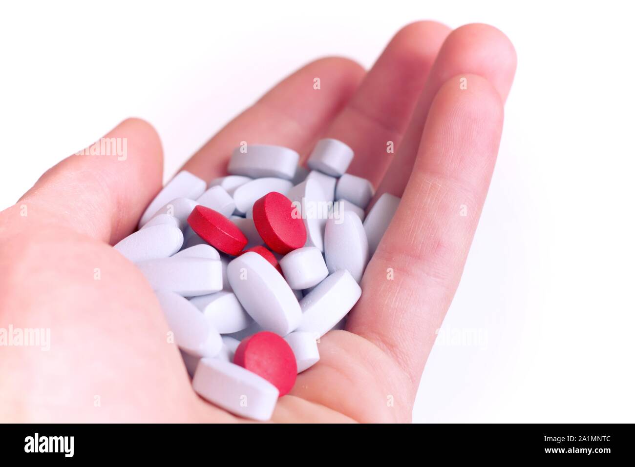 Drogenmissbrauch, Selbstmedikation, Placebo-Konzept. Handvoll rote und blaue Pillen auf weißem Hintergrund. Stockfoto