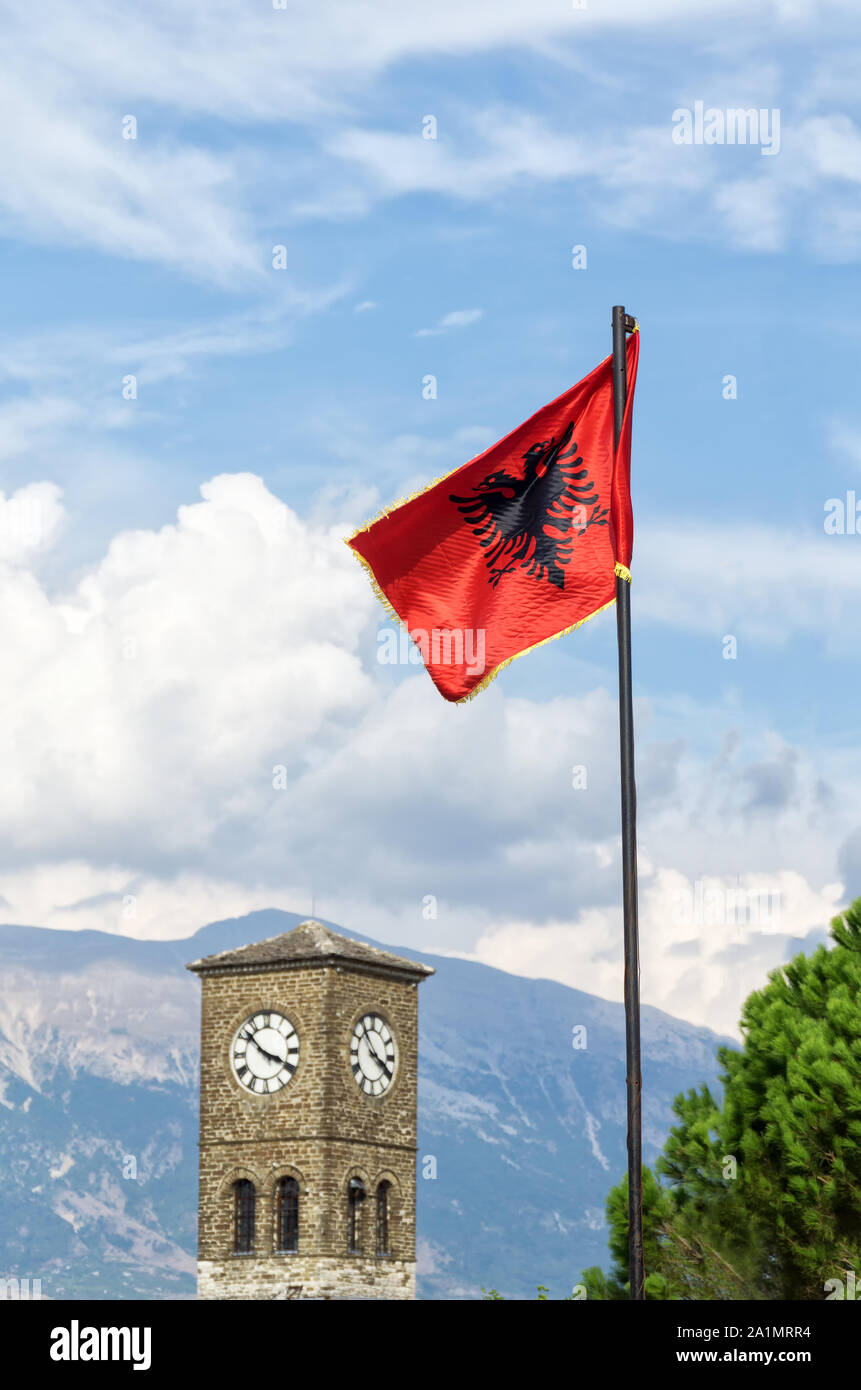 Der Uhrturm und Abanian Flagge auf gjirokastra Festung Schloss mit Berge und blauer Himmel mit weißen Wolken im Hintergrund. Selektive konzentrieren. Stockfoto