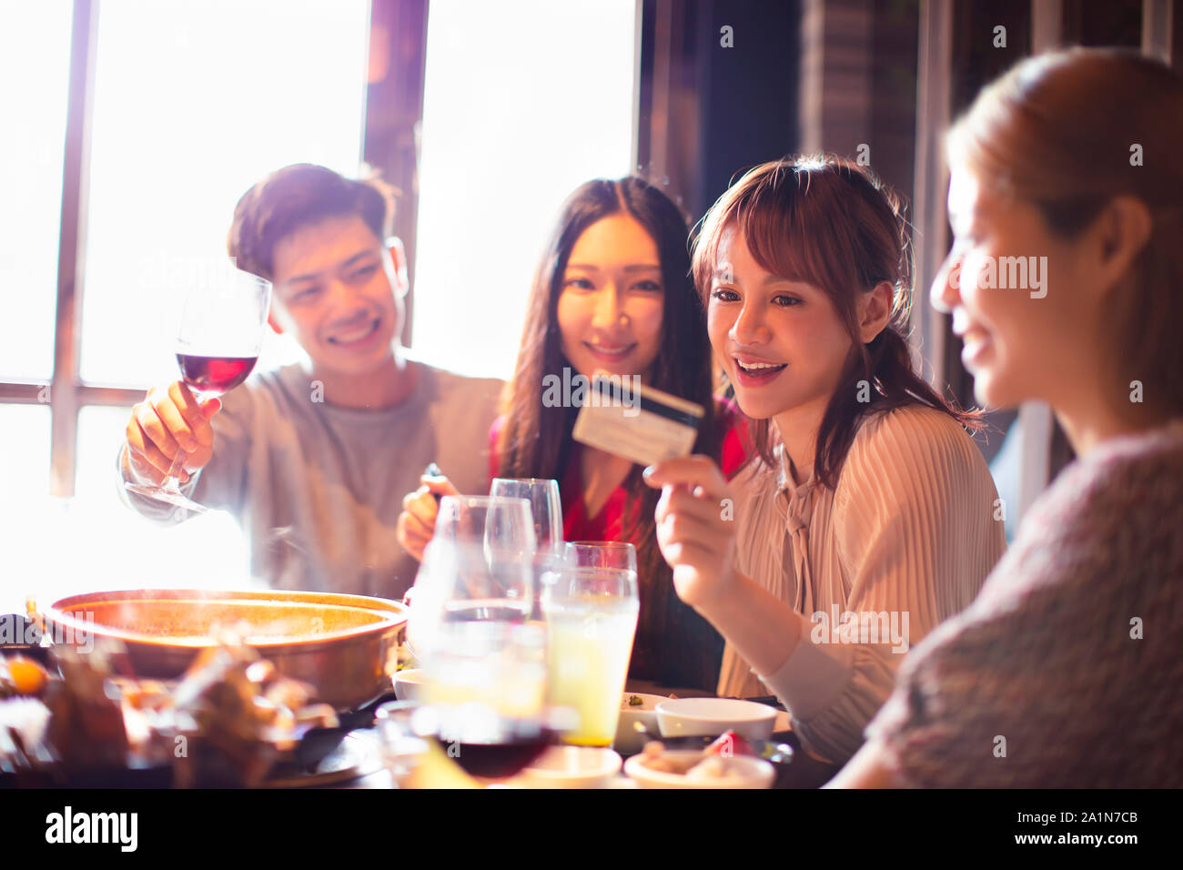 Glückliche junge Gruppe mit Kreditkarte und Chatten im Restaurant Stockfoto