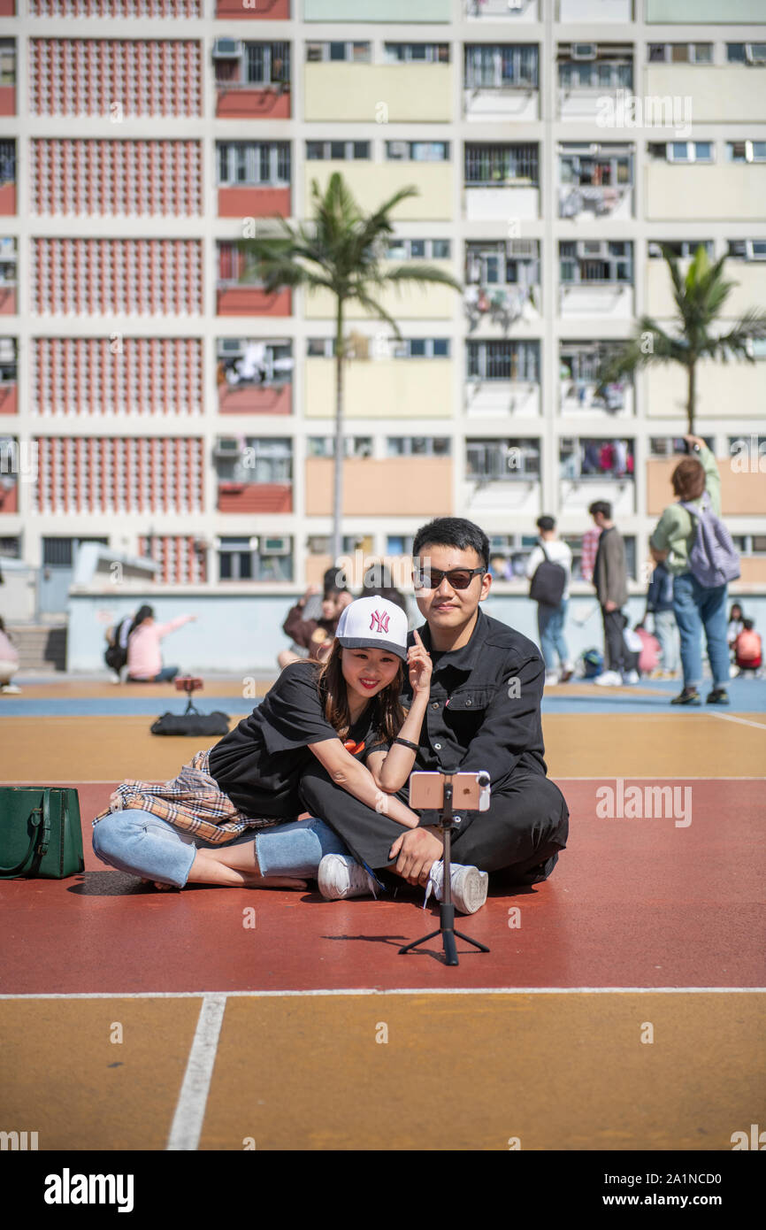 Chinesische Touristen nehmen eine selfie vor der Choi Hung öffentliche Wohnanlage in Hongkong. Stockfoto