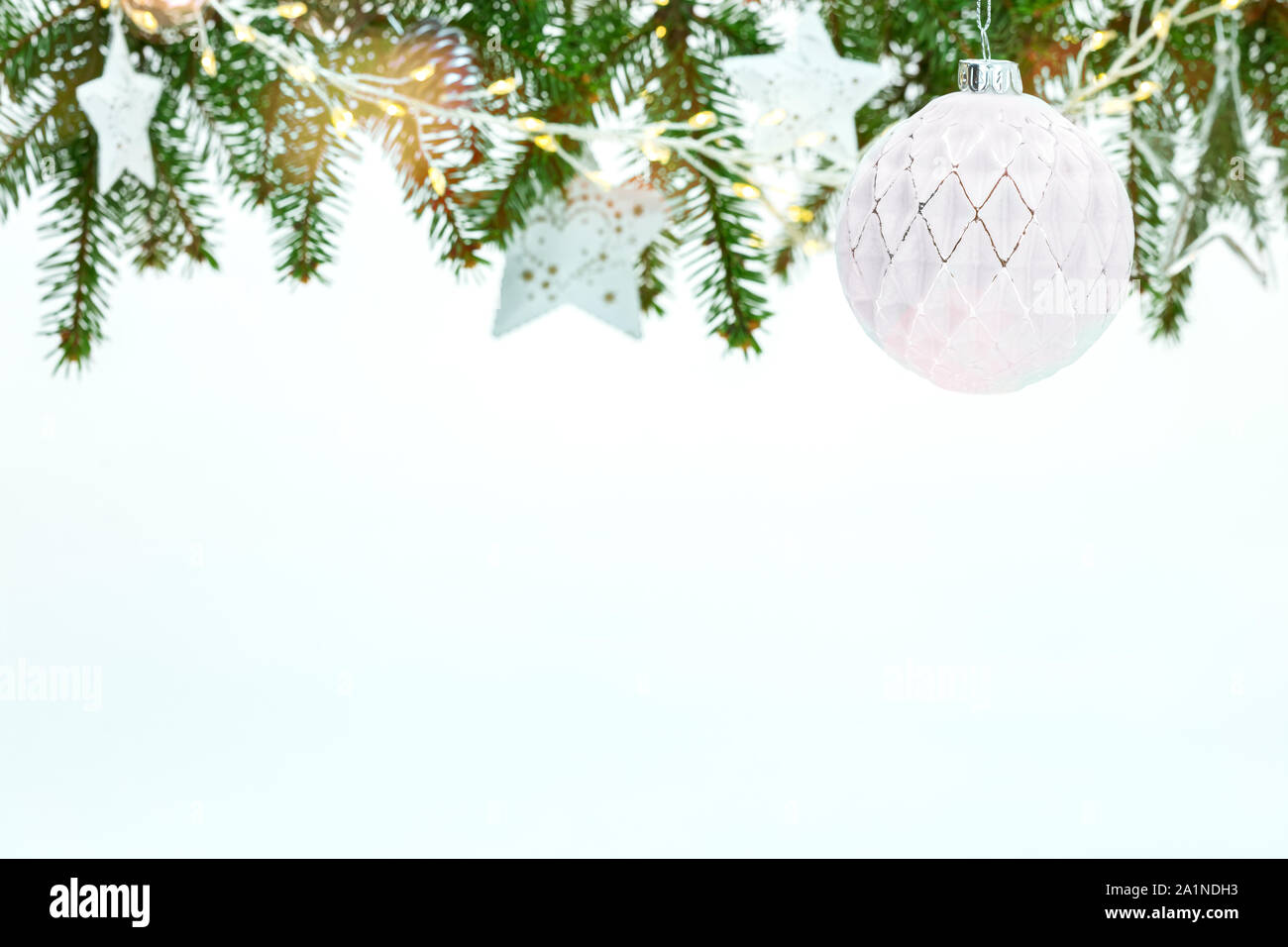 Schöne Weihnachten weißer Hintergrund mit grünen Tannenbaum Äste mit weißen Kugeln, Sternen und Lichtern geschmückt Stockfoto