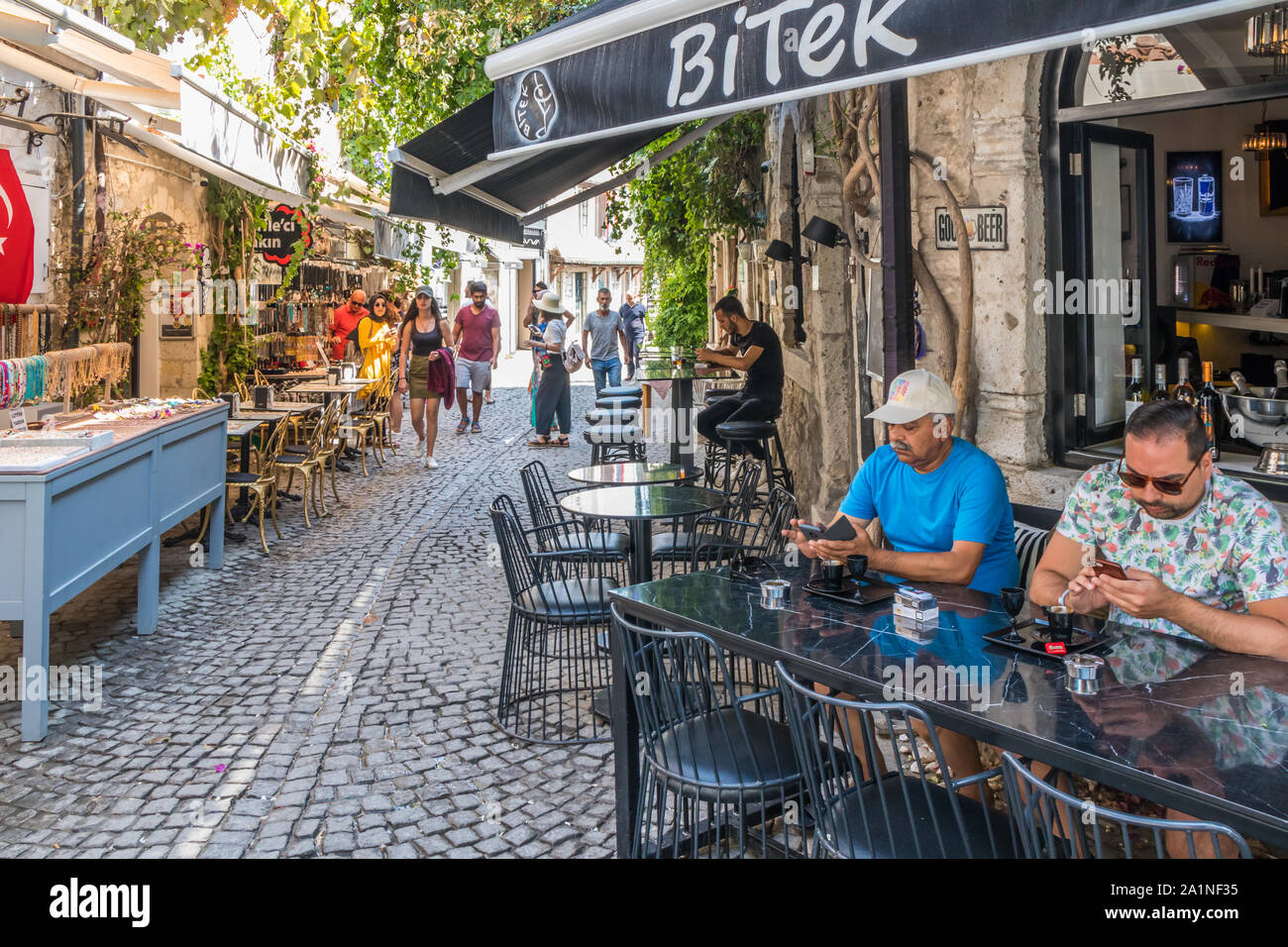 Alacati, Türkei - 4. September 2019: typischen schmalen gepflasterten Straße mit Cafés und Restaurants. Die Stadt ist bei Touristen beliebt im Sommer Stockfoto