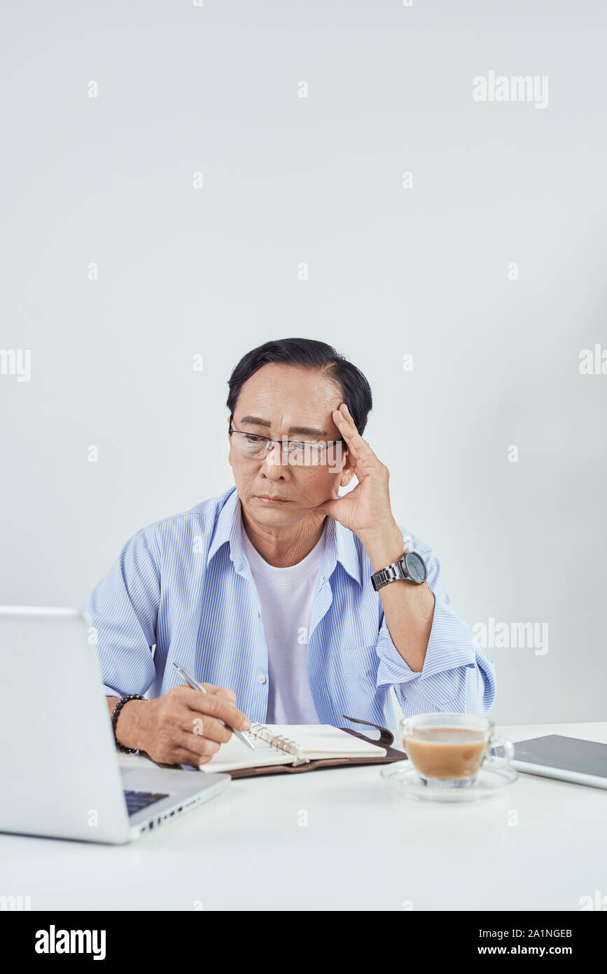 Älterer Mann sitzend vor seinem Laptop im Wohnzimmer sorgen Stockfoto