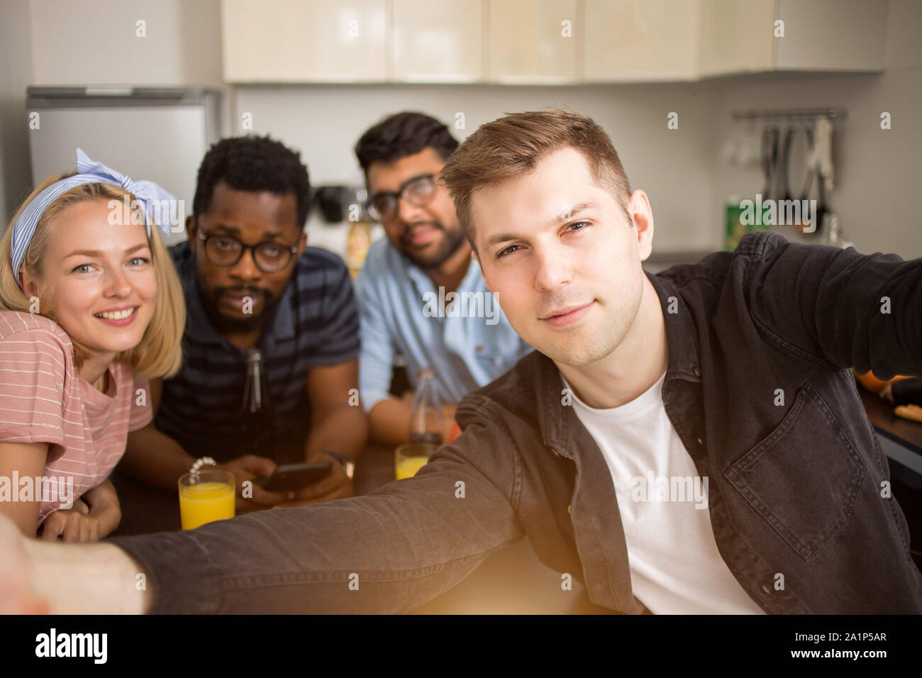 Sagen Käse. Stattlichen kaukasischen Mann unter selfie mit Freunden. Glücklich, multi-ethnische Studenten am Tisch sitzen und essen in der Küche zu Hause. Stockfoto