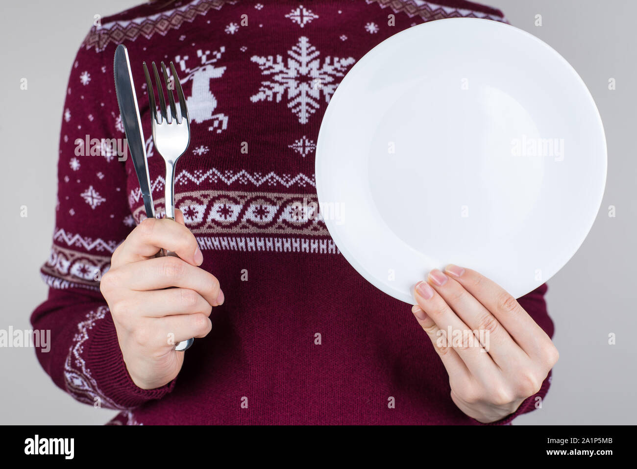 7/8 Nahaufnahme Foto von Händen, Silberbesteck und Weiße, runde Platte in Händen isoliert graue Farbe Hintergrund Stockfoto