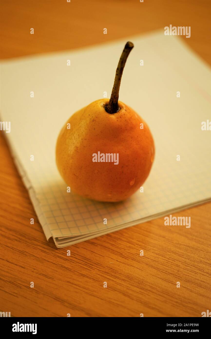 Orange Reife Birne Obst auf weißem Papier Notebook in einem Käfig Stockfoto