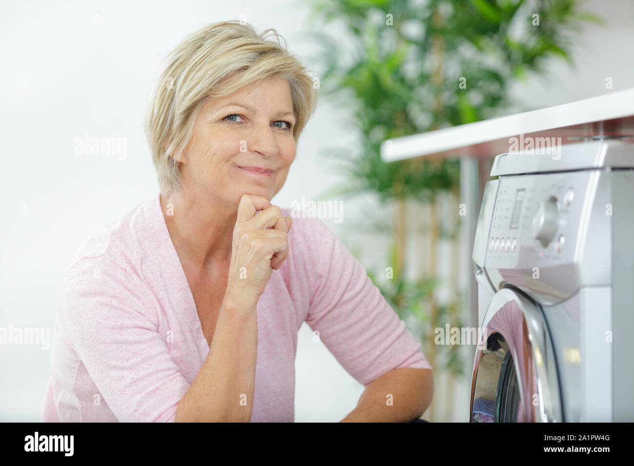 Ältere Frau laden Waschmaschine zu Hause Stockfoto