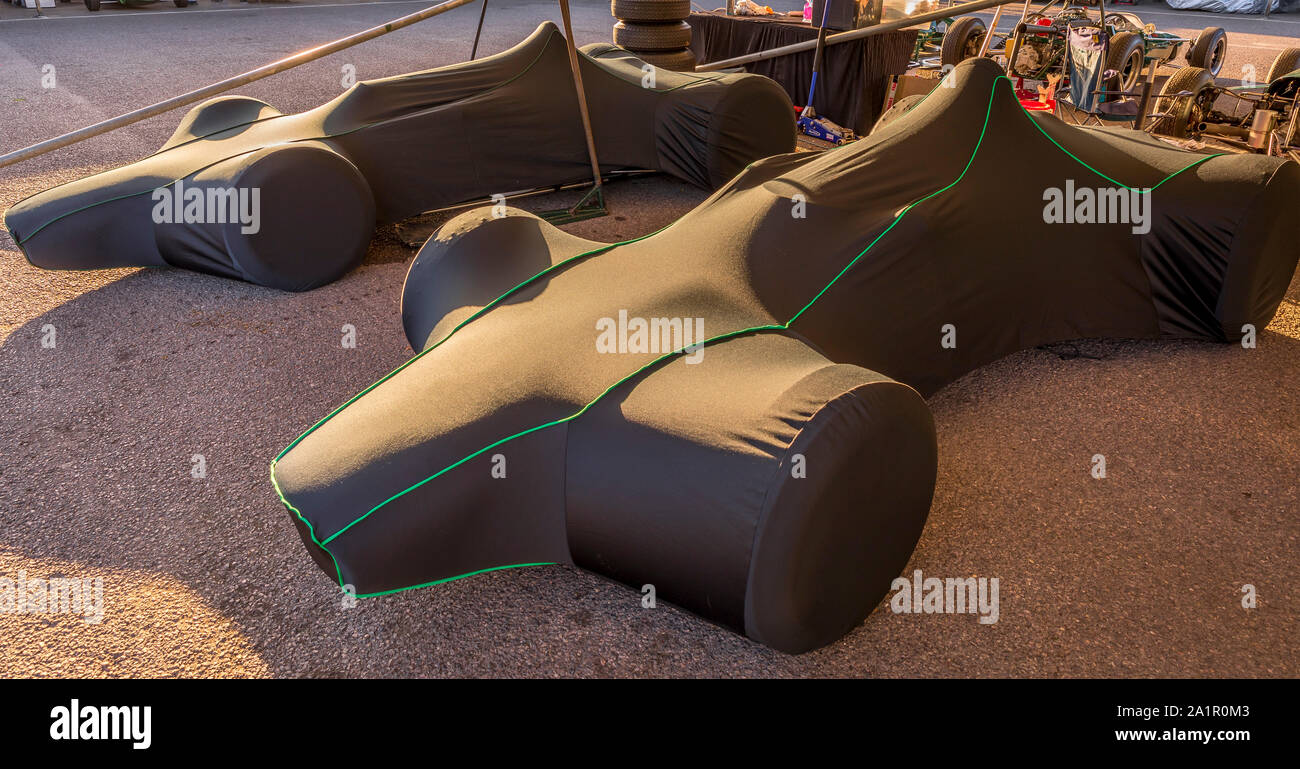 1963 Brabham-Climax BT7 und 1964 BT11 unter Abdeckungen im Fahrerlager garage earliy in den Morgen im 2019 Goodwood Revival, Sussex, UK. Stockfoto