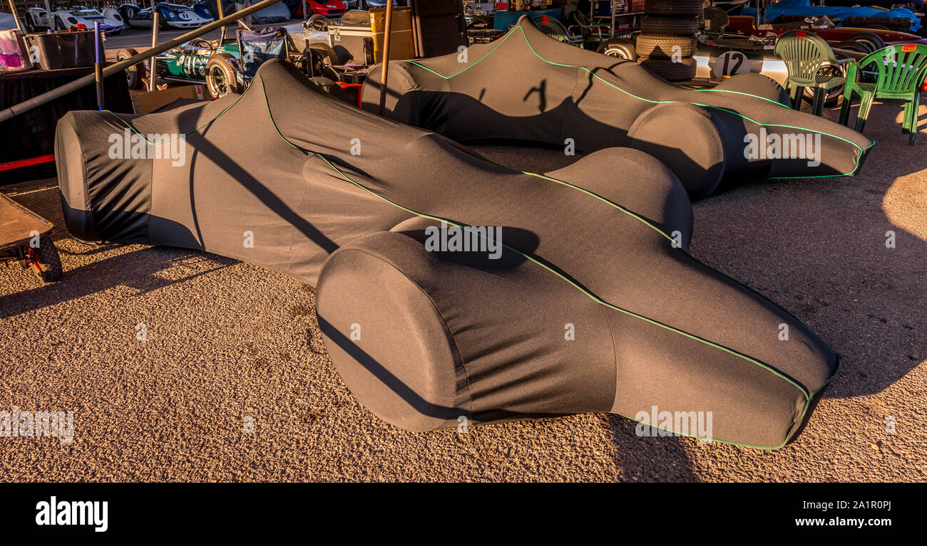 1963 Brabham-Climax BT7 und 1964 BT11 unter Abdeckungen im Fahrerlager garage earliy in den Morgen im 2019 Goodwood Revival, Sussex, UK. Stockfoto