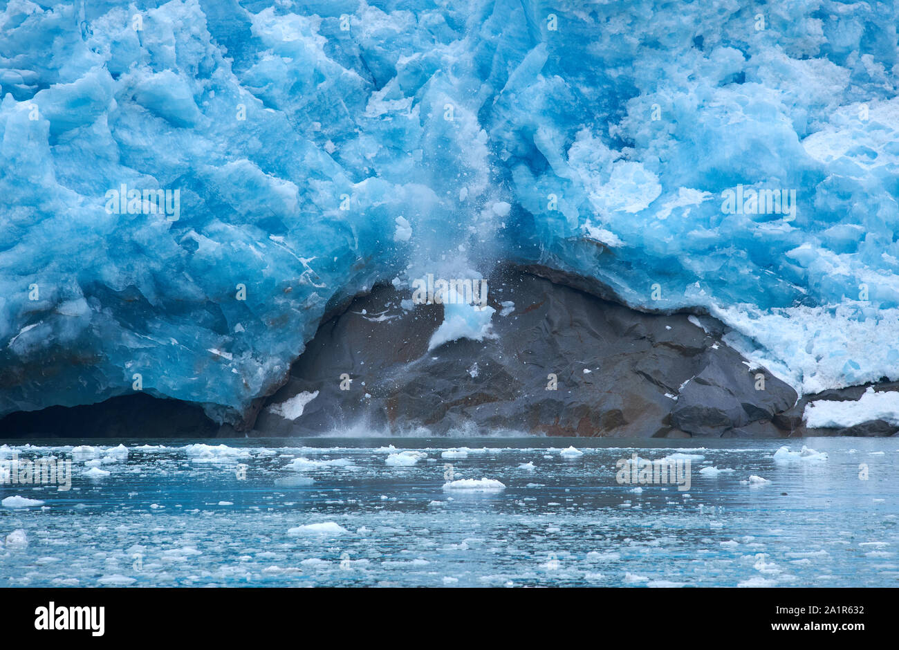 Ein Eisblock fällt ab und die vertikal geneigte Gletscherzunge des Northwestern Glacier und trifft auf einen Felsen (erstes von vier Fotos). Stockfoto