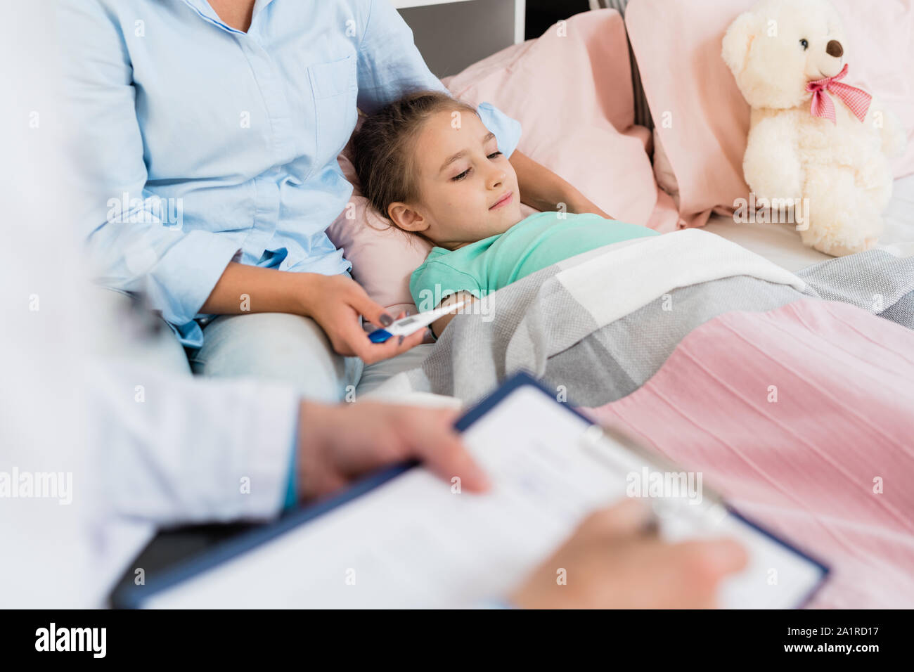 Kranker Kleiner Madchen Liegt Im Bett Unter Der Decke Wahrend Ihre Mutter Holding Thermometer Und Arzt Die Rezepte Stockfotografie Alamy