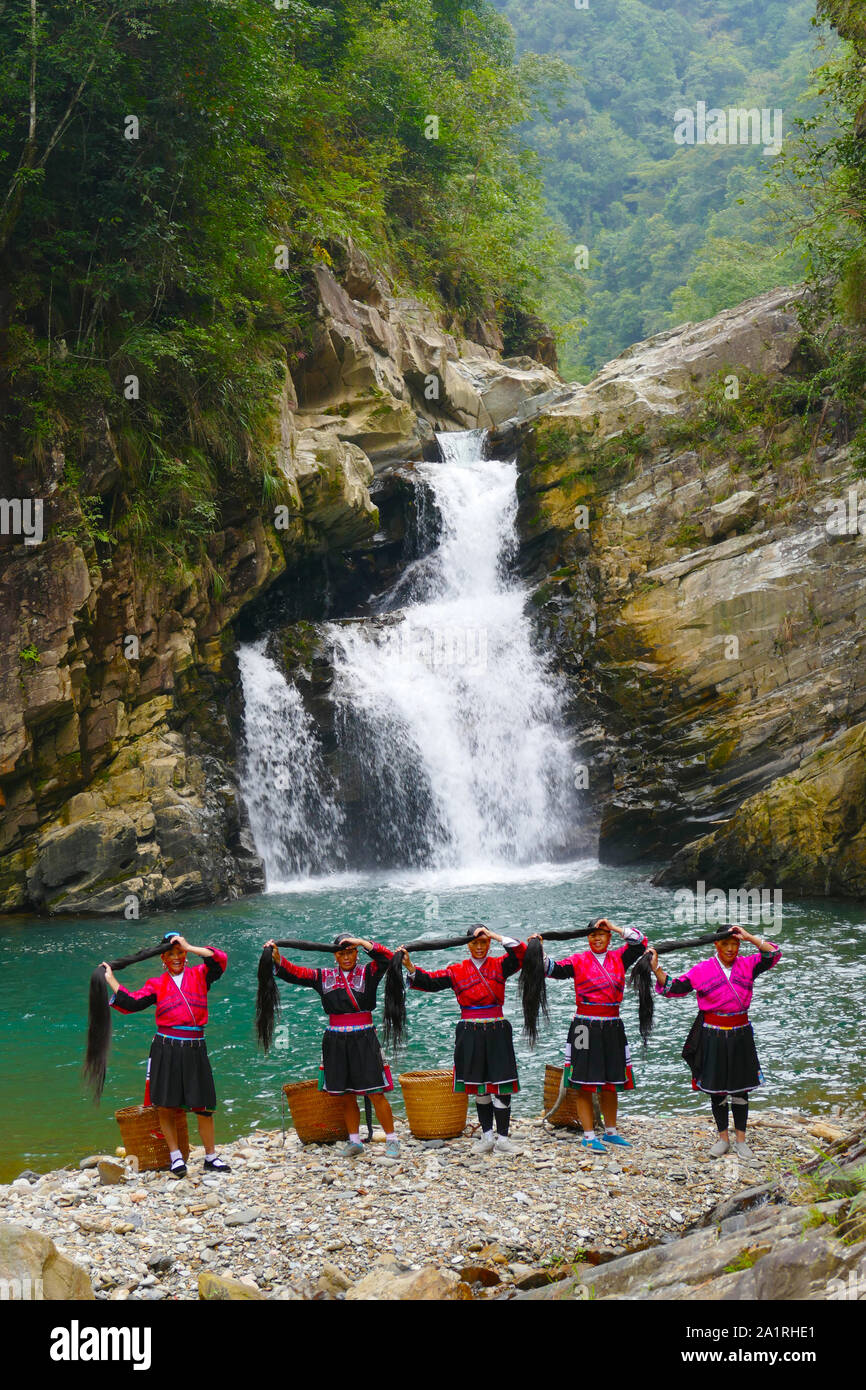 Das lange Haar Yao ethnischen Minderheiten angehörenden Frauen posiert von einem Wasserfall im Longsheng Reisterrassen in Ghuangxi Zhuang Autonome Region in China in der Nähe von G Stockfoto