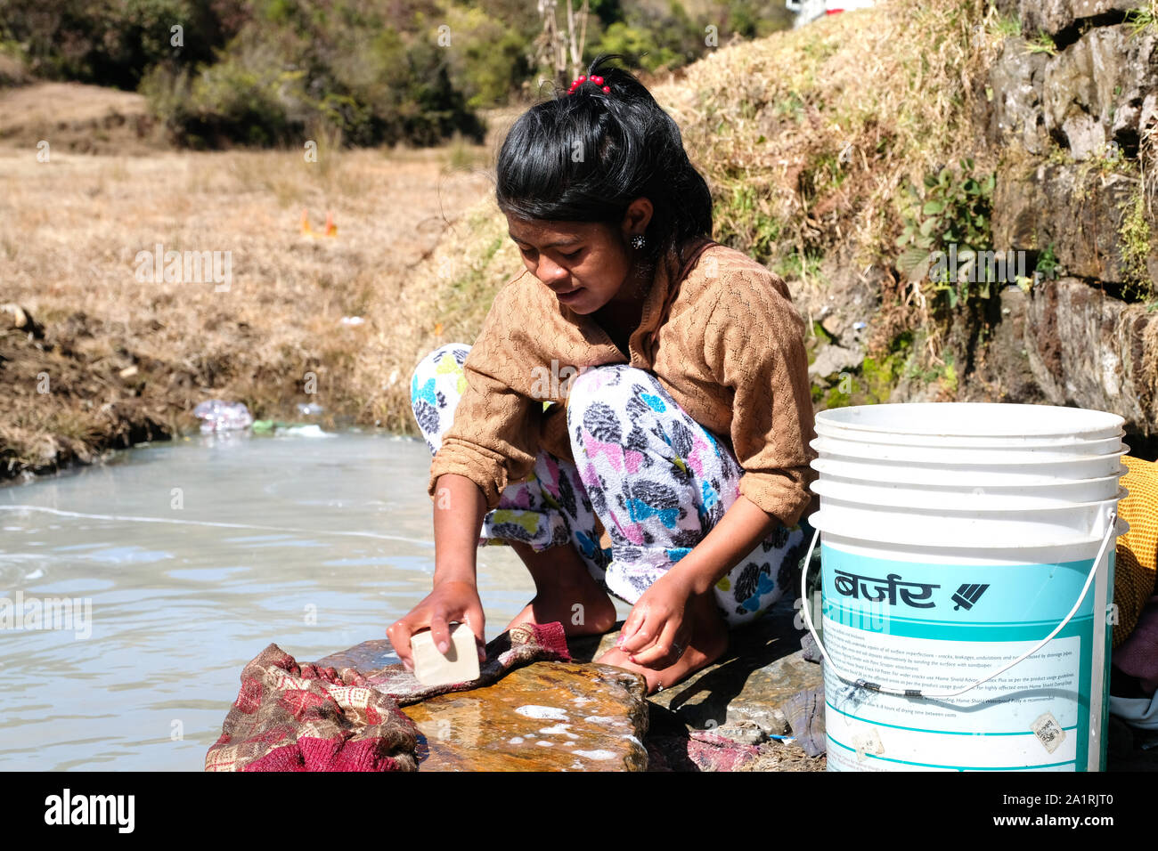 Frauen und Mädchen Kleidung waschen in einem schmutzigen Strom. Bundesstaat Meghalaya, Nordosten von Indien, Asien Stockfoto