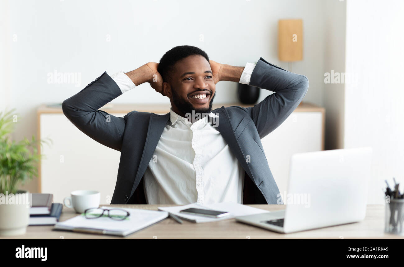 Schwarzer Geschäftsmann Entspannung am Arbeitsplatz, lehnte sich zurück in den Stuhl Stockfoto
