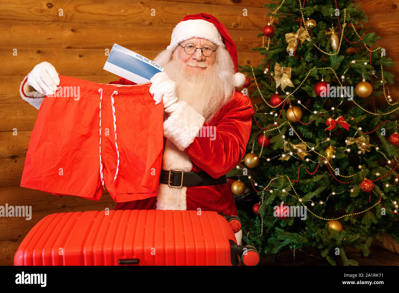 Santa-Übersicht der Weihnachtsgeschenke - rote Shorts und Flugtickets - bei der Stellung von eingerichtet firtree Stockfoto