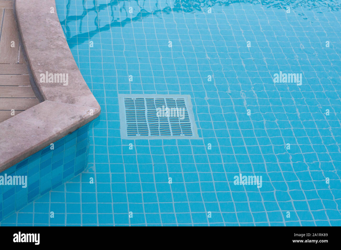 Quadratische weiße Bodenablauf in einem blau gefliesten Pool. Engineering Systeme im Pool