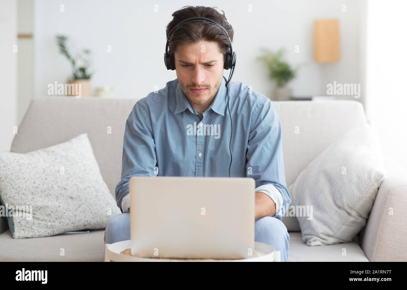 Ernster Kursteilnehmer in Kopfhörer Studieren an Laptop zu Hause Stockfoto
