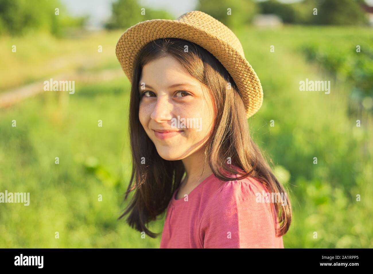 Outdoor Portrait von schönen lächelnde Mädchen 12, 13 Jahre alt in Hut, Natur Hintergrund goldenen Stunde Stockfoto