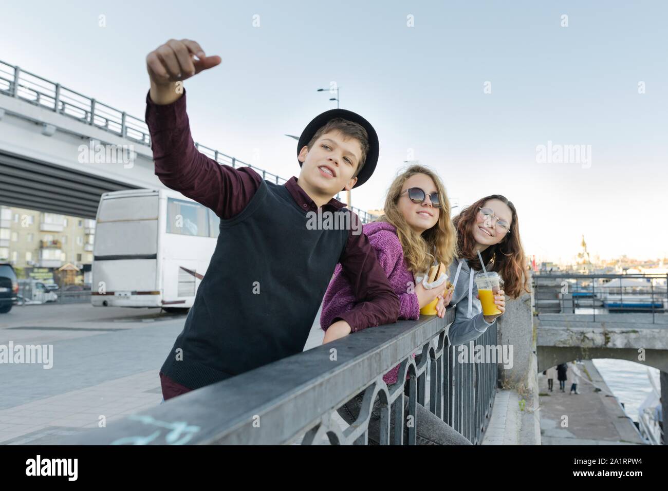 Jugendliche Jungen und zwei Mädchen mit Street Food sprechen Outdoor. Stockfoto