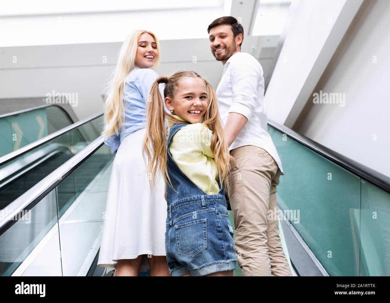 Familie Lächeln auf die Kamera auf der Rolltreppe in Mall Centre Stockfoto