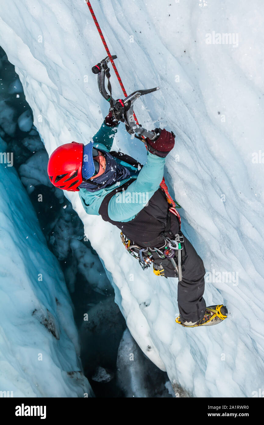 Weibliche Eiskletterer schwingen Eis Werkzeug in Gletschereis. Ice Climbing guide Klettern harte Linie in eine Gletscherspalte auf der Matanuska Gletscher in Alaska. Stockfoto