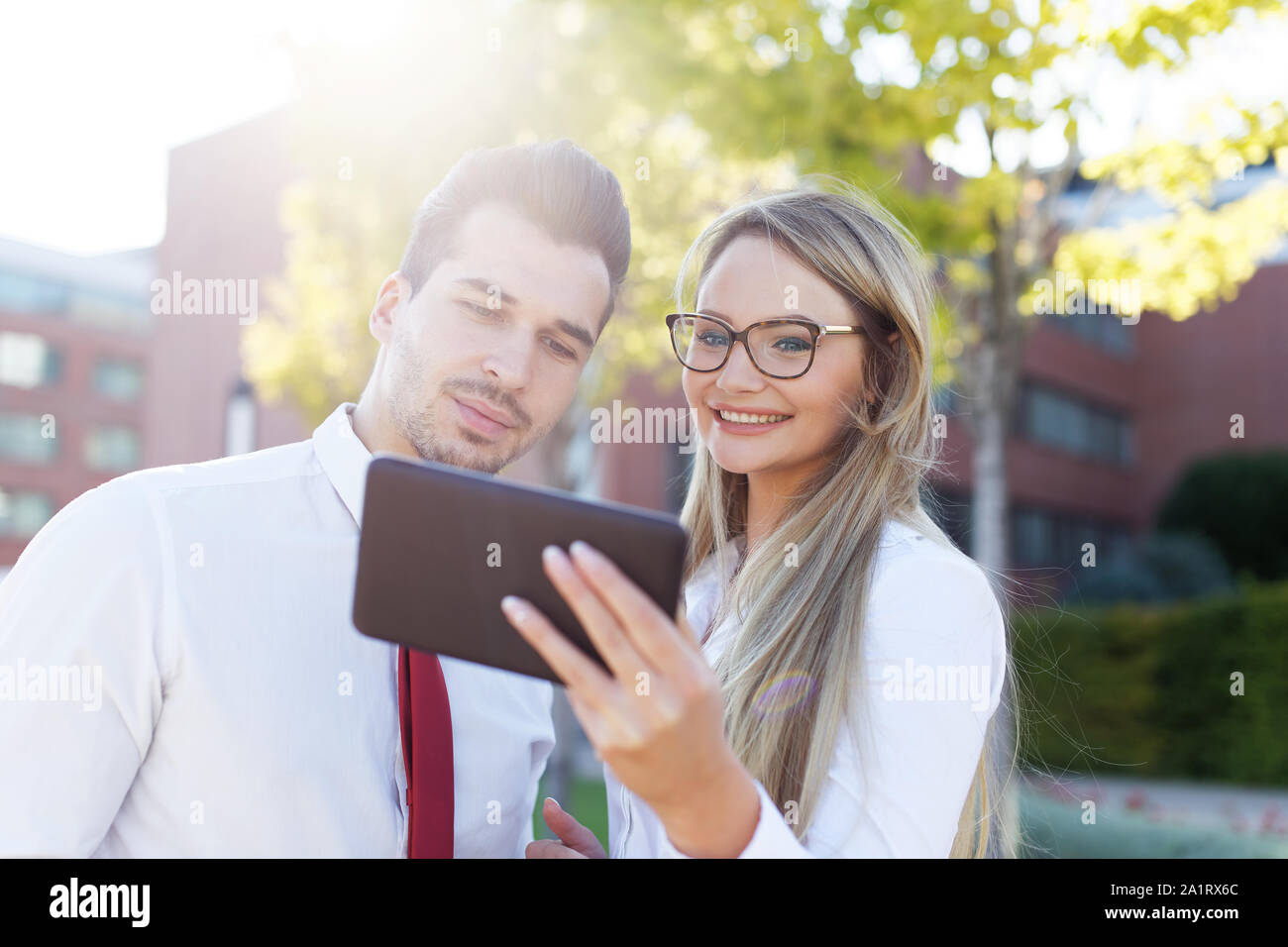 Glückliche junge Geschäftsleute lesen auf Tablet finanziellen Ergebnisse im Freien Stockfoto