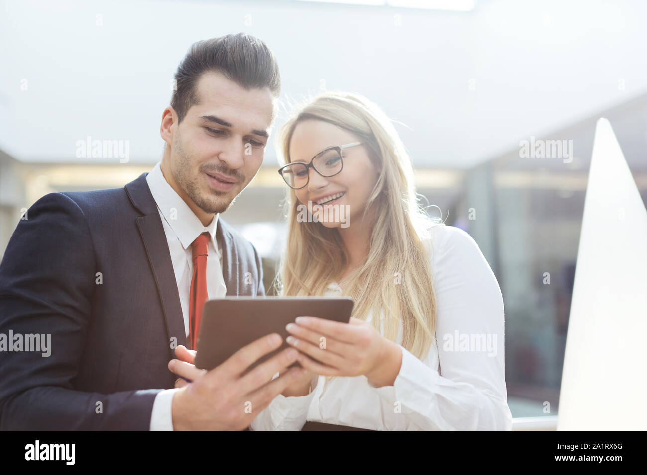 Glückliche junge Geschäftsleute lesen auf digital Tablet im Innenbereich Stockfoto