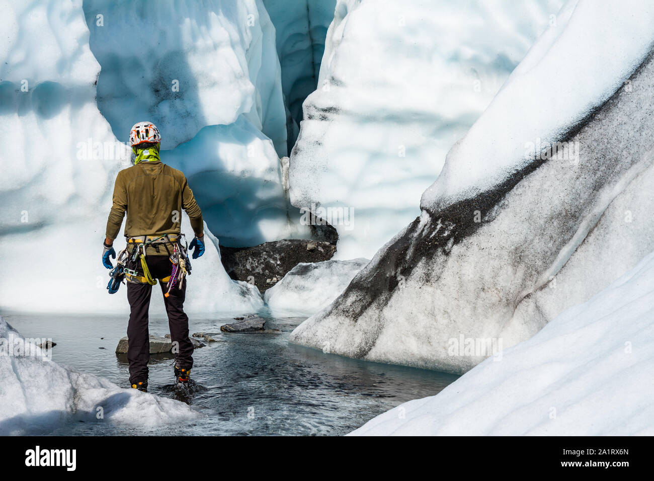 Ice climbing Guide durch einen Canyon voll von seichten Wasser führt zu einem Eingang eines Ice Cave auf der Matanuska Gletscher in Alaska. Stockfoto