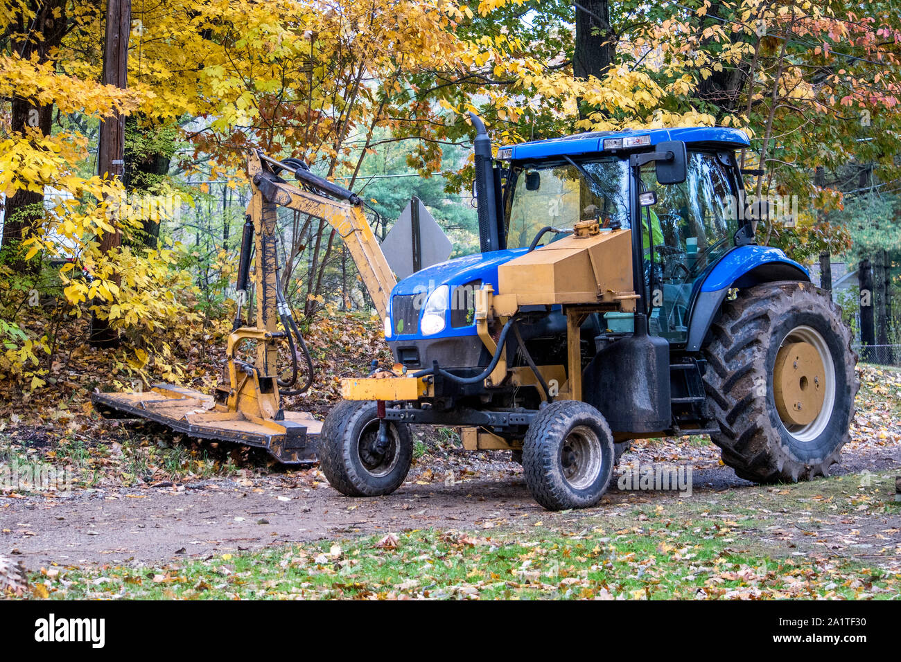 Ein großer Traktor mit einem riesigen mähen Deck, schneidet zurück Straße Seite über Wachstum in ländlichen Michigan USA Stockfoto