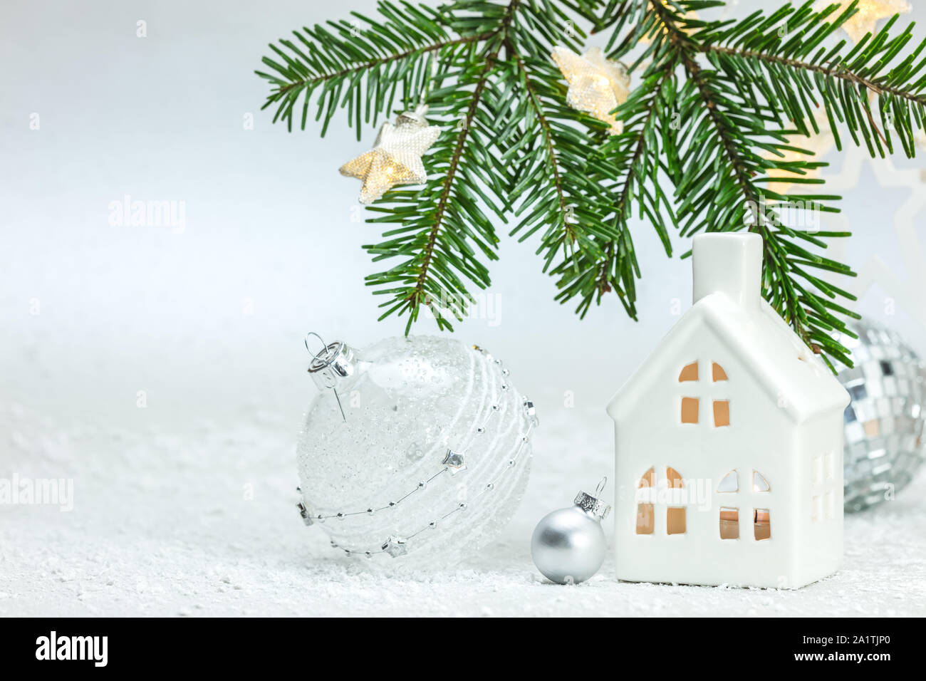 Frohe Weihnachten Zusammensetzung mit grünen Fir Tree Branch, Stern leuchten, Spielzeug, Haus und Bälle gegen weisse Schneelandschaft Hintergrund Stockfoto