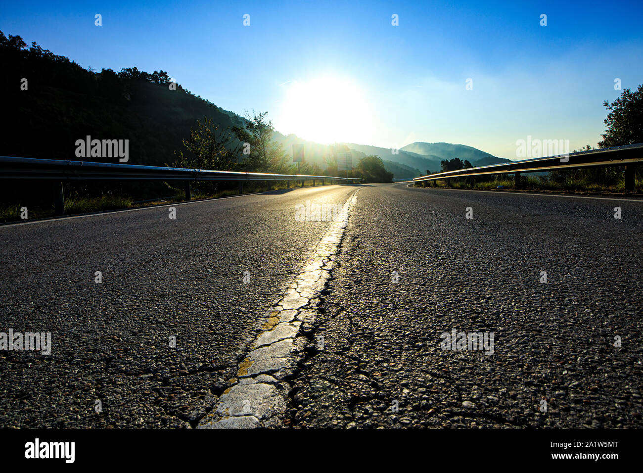 Schwarz Breite leer Asphaltstraße mit weißen Linie mit Sonne auf blauem Himmel Stockfoto