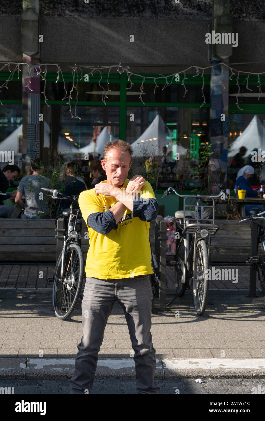 Sint Niklaas, Belgien, September 8, 2019, Man praktiziert Falun Dafa, verschränkte seine Arme und beide Schultern berühren Stockfoto