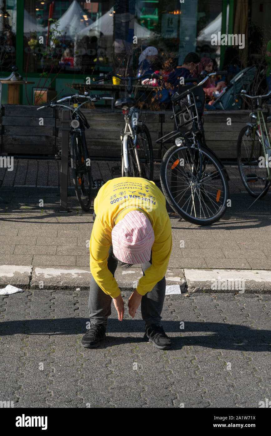 Sint Niklaas, Belgien, September 8, 2019, Orientalische Frau mit Hut praktiziert Falun Dafa, beugt sich über und lässt beide Arme hängen Stockfoto