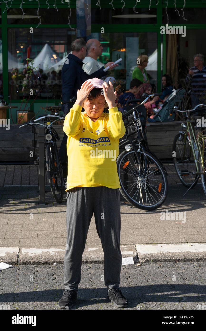 Sint Niklaas, Belgien, September 8, 2019, Orientalische Frau mit Hut praktiziert Falun Dafa, atmet Leistungsstarke und senken Sie die Arme nach unten Stockfoto