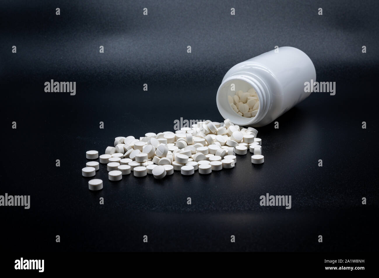 Ein Haufen weiße Pillen vor einer halb leeren Flasche Stockfoto